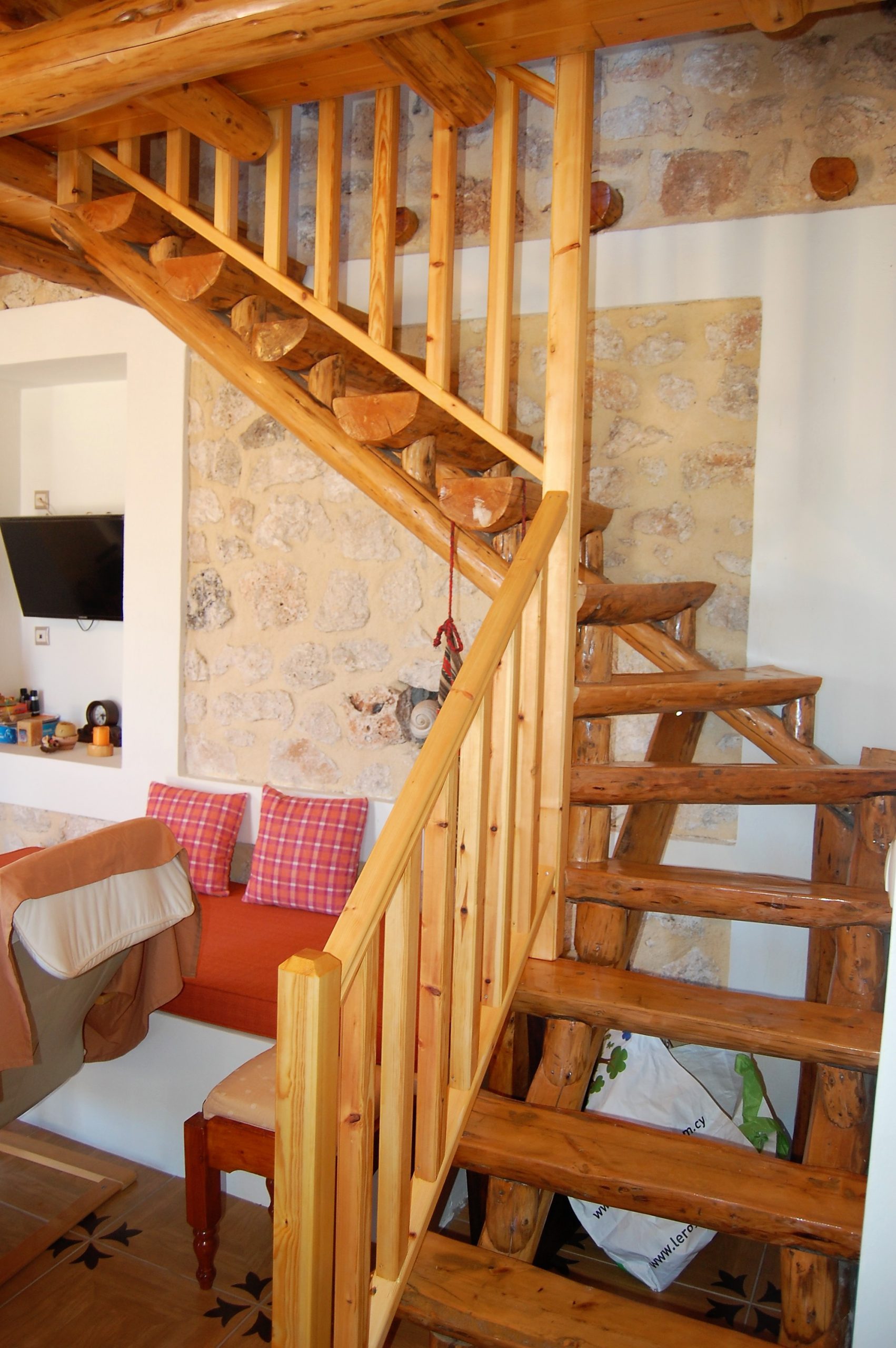 Open plan lounge with wooden staircase of stone house for rent Ithaca Greece