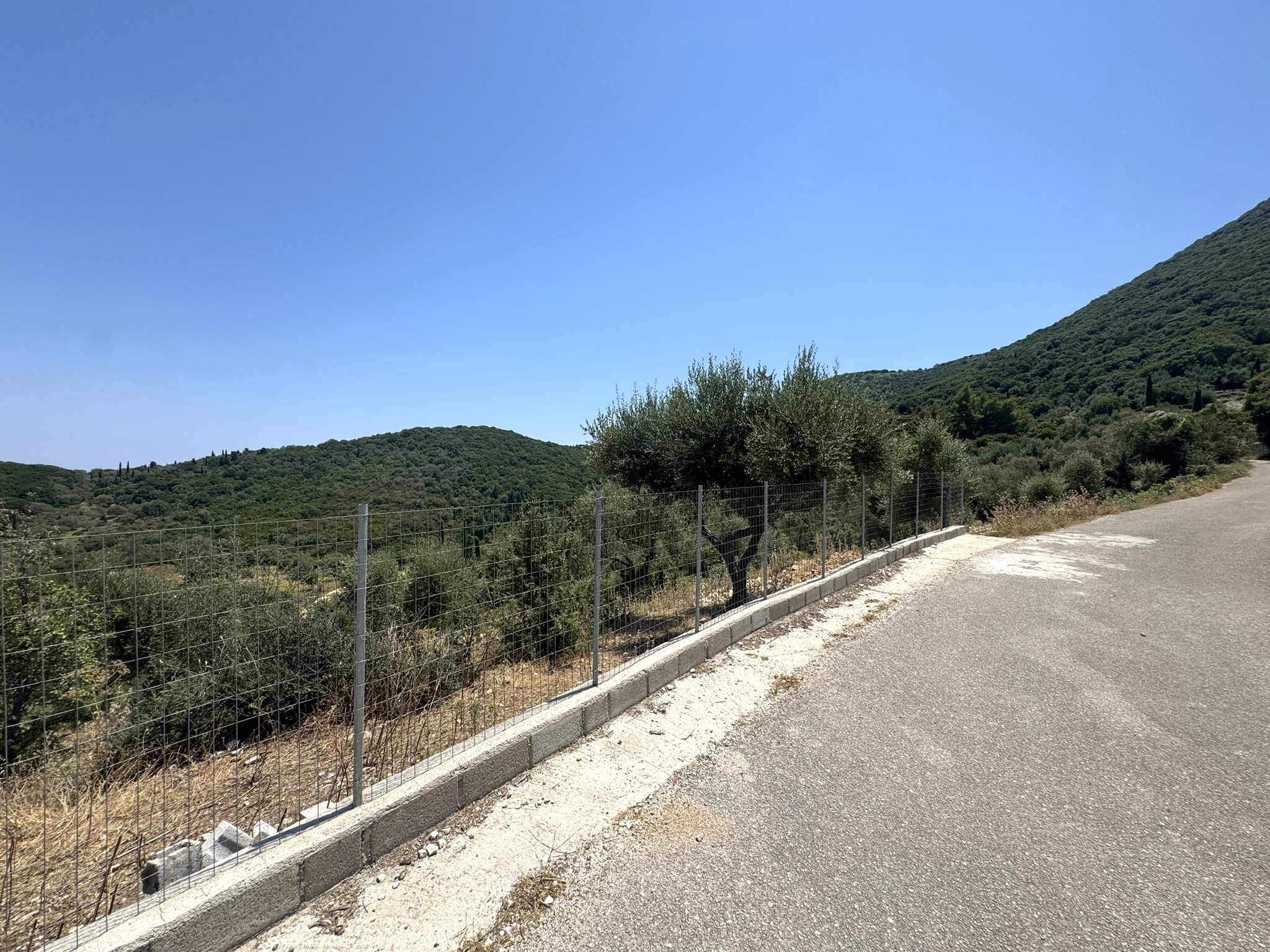 Road view of land with building license for sale in Ithaca Greece, Vathi