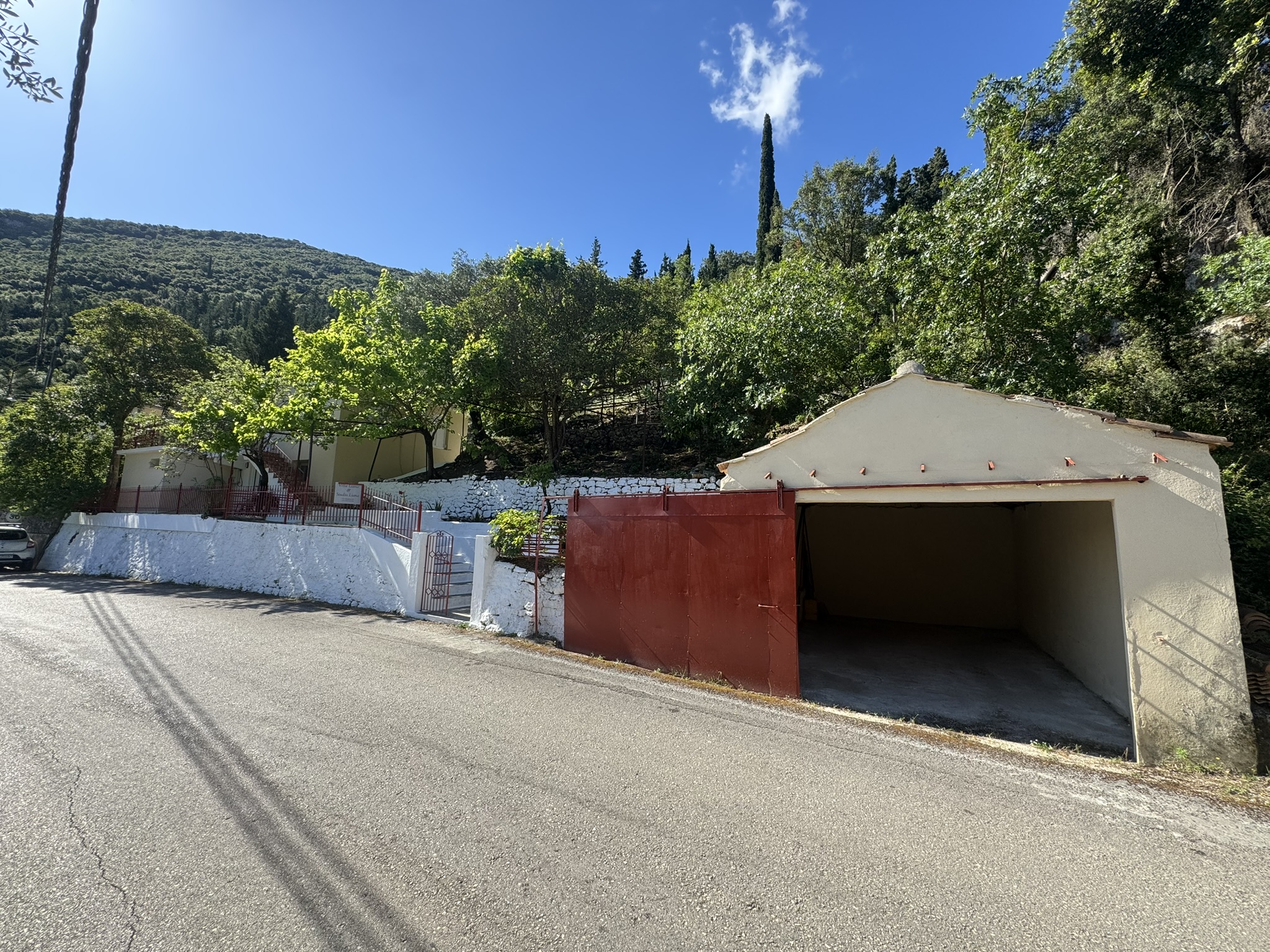 Road view and garage of house for sale in Ithaca Greece Frikes